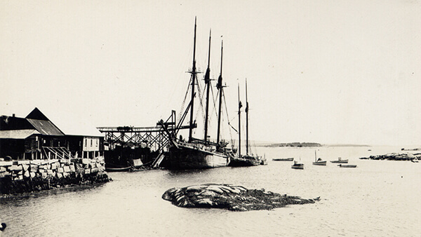 A black and white photo of an old hsip at a dock