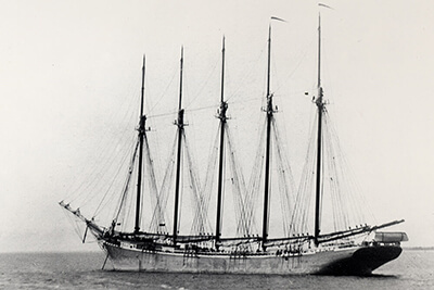 A black and white photo of a 5 masted ship
