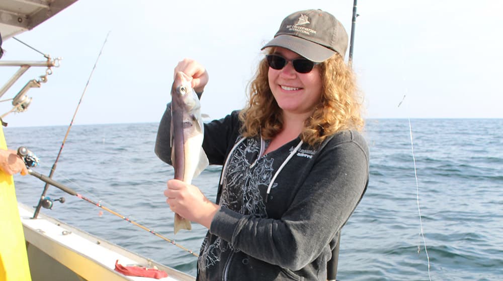 a women on a boat holding a fish she caught