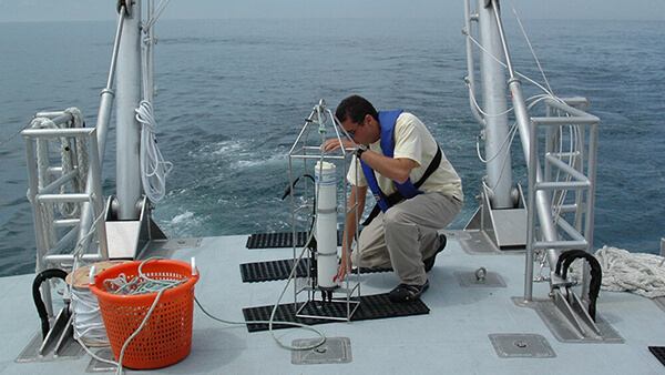 a person the deck of a ship prepares research equipment