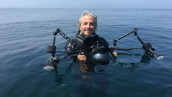 Keith Ellenbogen poses for a photo holding an underwater camera