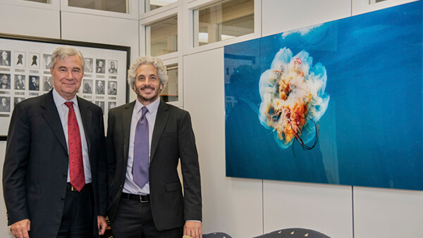 Kieth Ellenbogen poses with Senator Sheldon Whitehouse next to a print of one of his photos