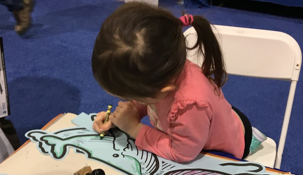 A kid drawing with crayons